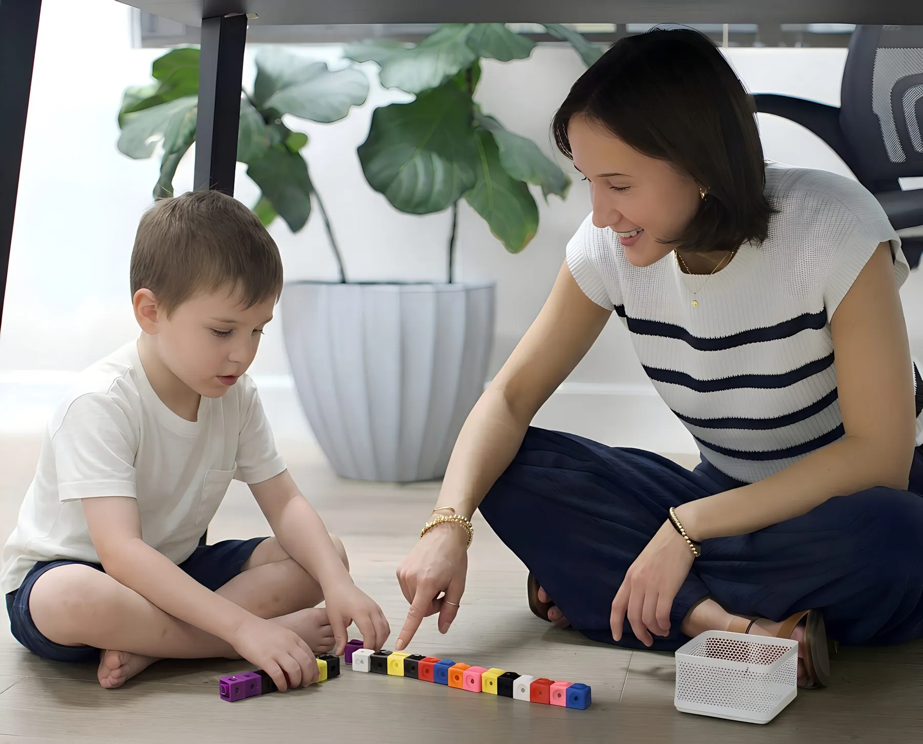 An Arcadia instructor and a young student counting with colored cubes on the floor